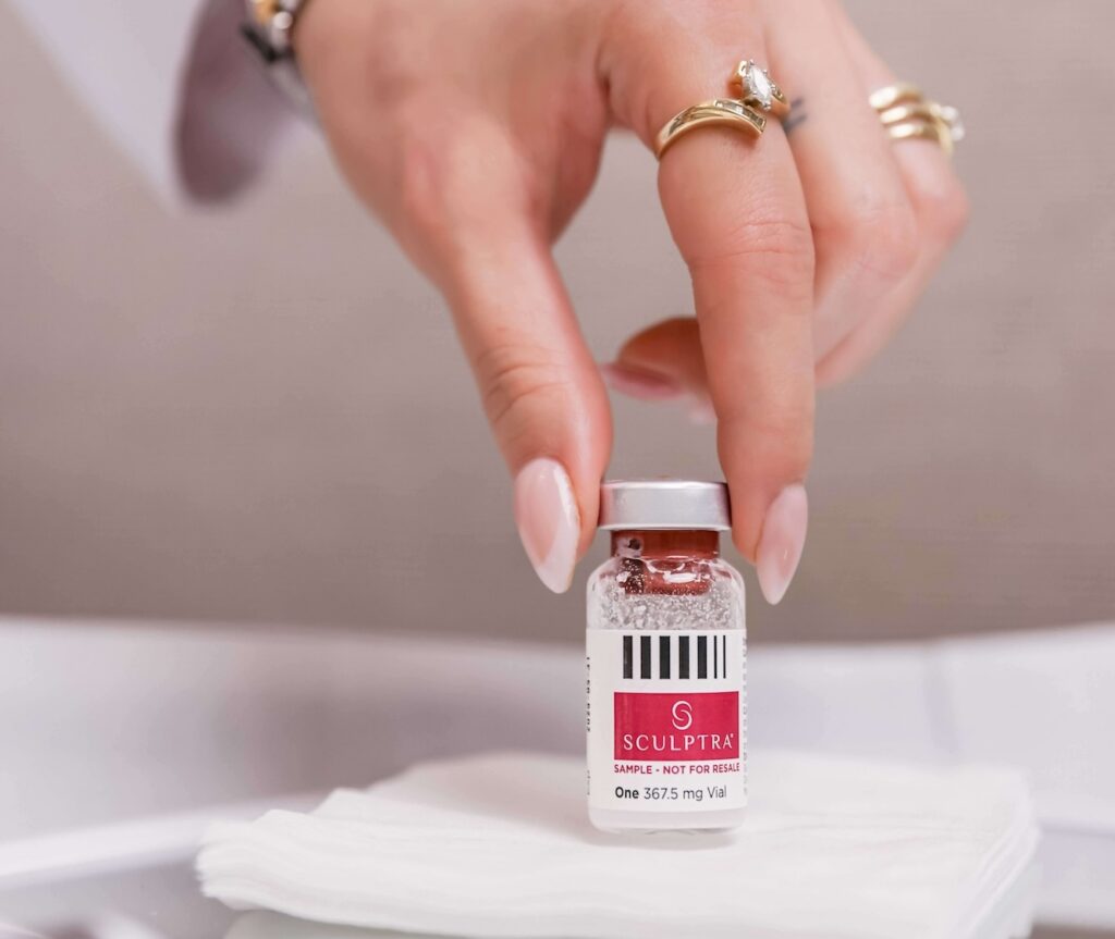 Close-up of a woman's hand hold a vial of Sculptra, and example of just one of the products that could be your best filler in St. Louis.